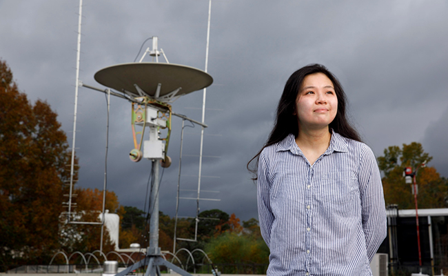 Alex Lin photographed in front of the antenna of the small satellite ground station on the roof of the Geography Geology Building. (Photo by Peter Frey/UGA)
