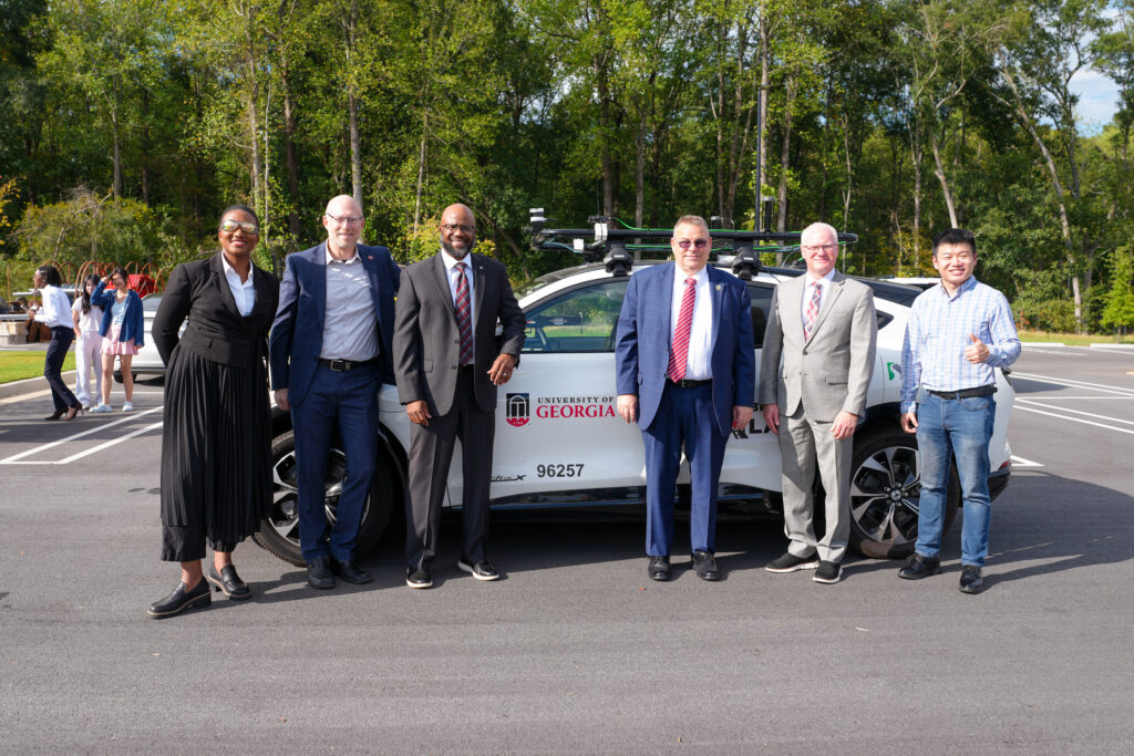 A row of people standing in front of a vehicle labeled Future Mobility Living Lab