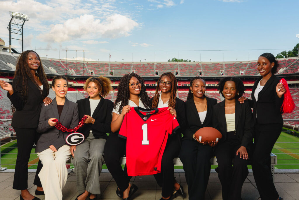 group of students in front of football field holding jersey