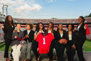 group of students in front of football field holding jersey