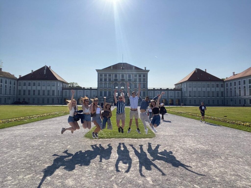 Group of students jumping up and posing for photo in front of location in Germany