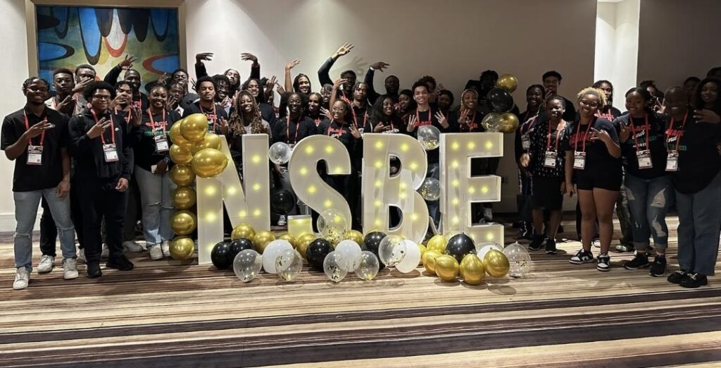 Group of students stands with big letters spelling "NSBE"