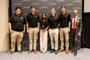 group of capstone students posing with dean and faculty