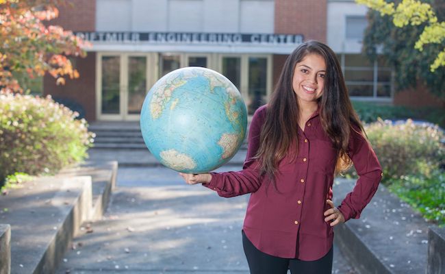 Dayrin Mendez holding a globe in front of the engineering building.