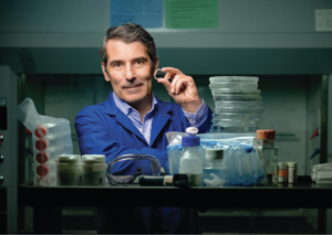 Eduardo Silva in a dim lab holds up a small contraceptive ring that his lab is developing.