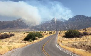 Road leading to a mountain with wildfire smoke coming from it